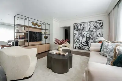 Living room at Dahlia with cream boucle armchairs, a television unit and monochrome artwork