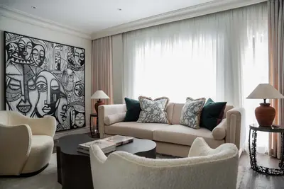Living room corner at Dahlia with face-print artwork and boucle armchairs